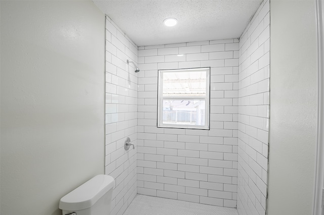 bathroom featuring a tile shower, a textured ceiling, and toilet