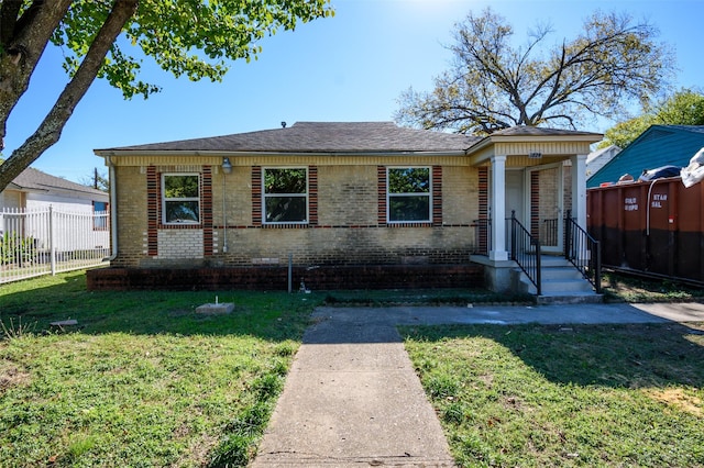 bungalow with brick siding, a front lawn, and fence