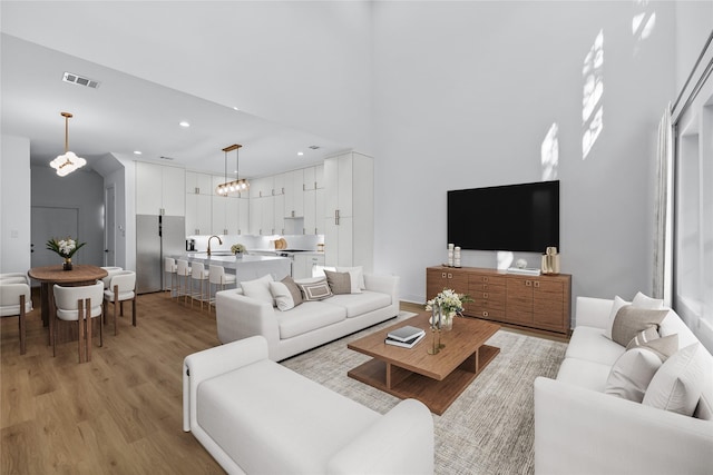 living room with sink, light hardwood / wood-style floors, and a towering ceiling