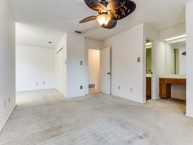 carpeted empty room featuring a textured ceiling, built in desk, and ceiling fan