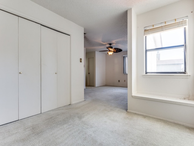 unfurnished bedroom with a textured ceiling, light colored carpet, and ceiling fan