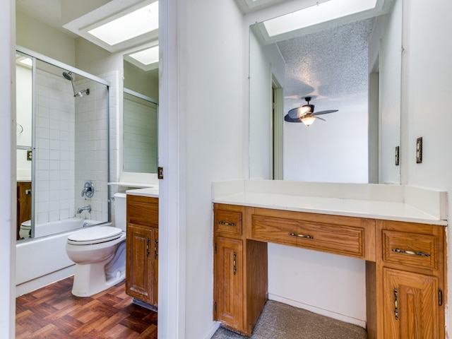 full bathroom with toilet, bath / shower combo with glass door, a textured ceiling, vanity, and ceiling fan