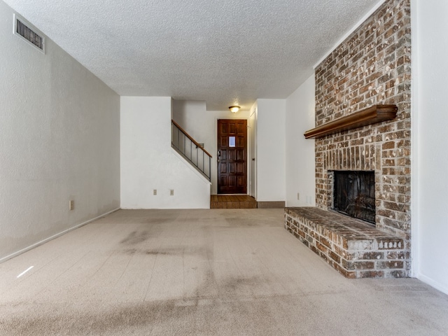 unfurnished living room with a brick fireplace, carpet, and a textured ceiling