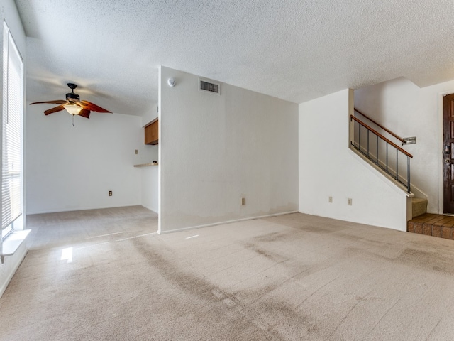 unfurnished living room featuring ceiling fan, a textured ceiling, and light carpet