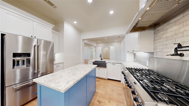 kitchen featuring appliances with stainless steel finishes, sink, white cabinets, a center island, and light hardwood / wood-style flooring