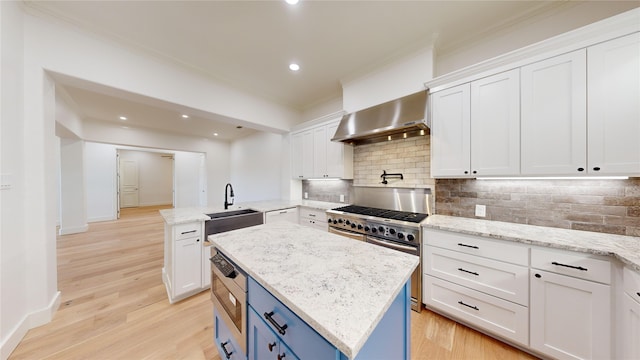 kitchen with white cabinetry, wall chimney range hood, and a kitchen island