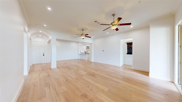 unfurnished living room with crown molding, ceiling fan, and light hardwood / wood-style flooring