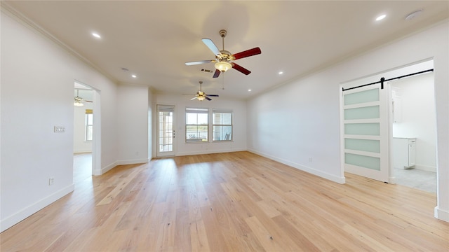 unfurnished living room featuring ceiling fan, ornamental molding, a barn door, and light hardwood / wood-style floors