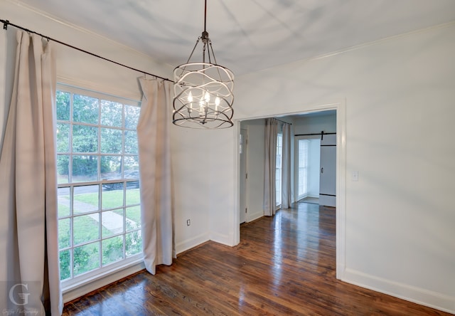 unfurnished dining area with a healthy amount of sunlight, dark wood-type flooring, a barn door, and a chandelier