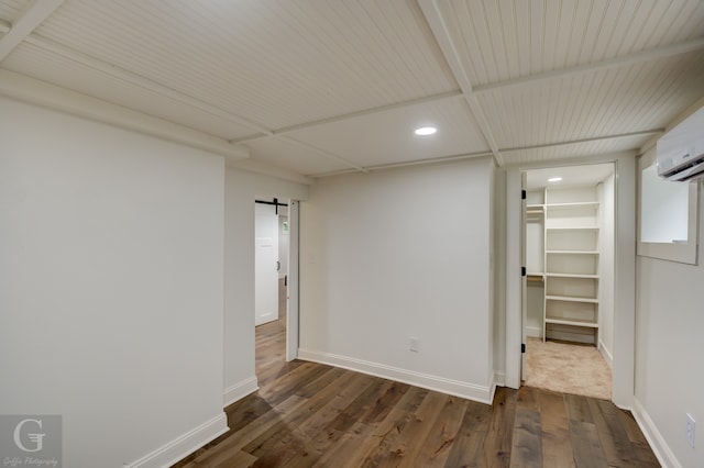 unfurnished room featuring a barn door, an AC wall unit, and dark hardwood / wood-style flooring