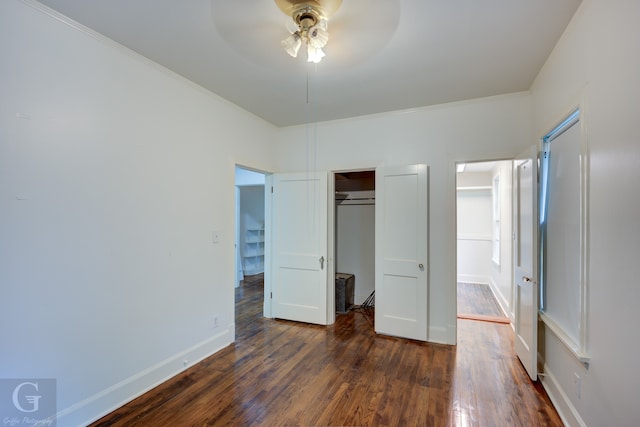 unfurnished bedroom with ornamental molding, dark hardwood / wood-style flooring, ceiling fan, and a closet