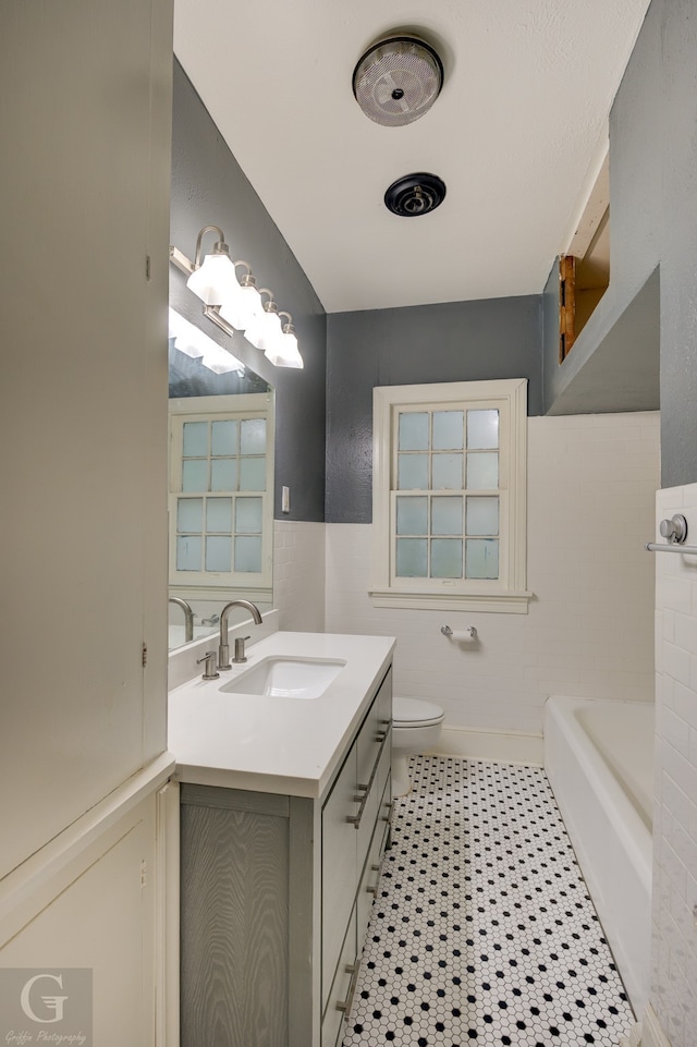 bathroom featuring vanity, toilet, and a washtub