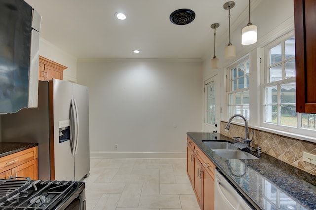 kitchen featuring tasteful backsplash, appliances with stainless steel finishes, pendant lighting, sink, and dark stone countertops