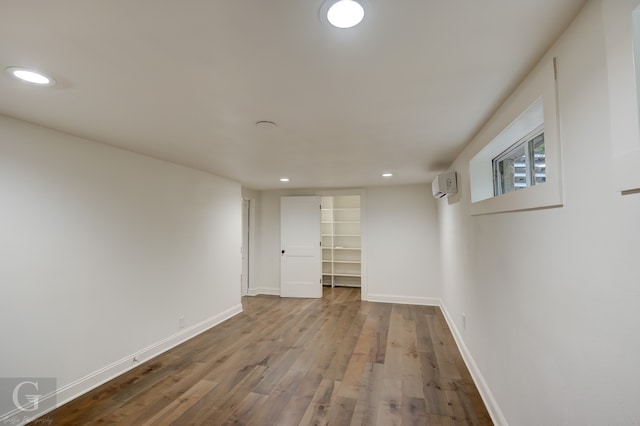 interior space with wood-type flooring and an AC wall unit