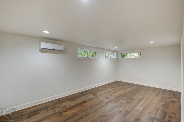 basement featuring a wealth of natural light, hardwood / wood-style flooring, and a wall mounted AC