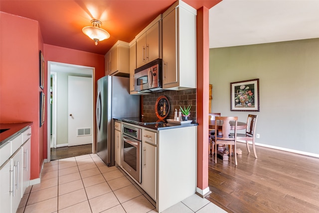 kitchen with white cabinetry, light wood-type flooring, appliances with stainless steel finishes, and tasteful backsplash