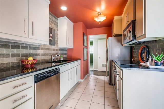 kitchen with sink, tasteful backsplash, light tile patterned flooring, white cabinetry, and appliances with stainless steel finishes