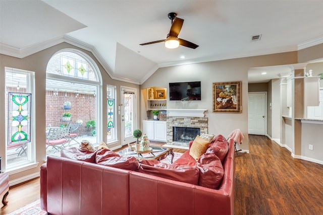 living room featuring lofted ceiling, dark wood-type flooring, crown molding, ceiling fan, and a fireplace