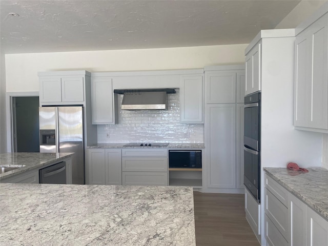 kitchen with light stone countertops, sink, stainless steel double oven, and gray cabinetry