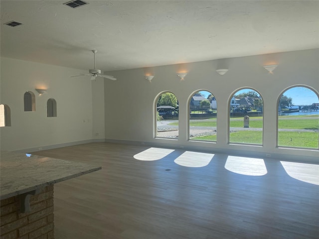 kitchen featuring light hardwood / wood-style flooring, a center island with sink, stainless steel refrigerator with ice dispenser, light stone counters, and a kitchen bar