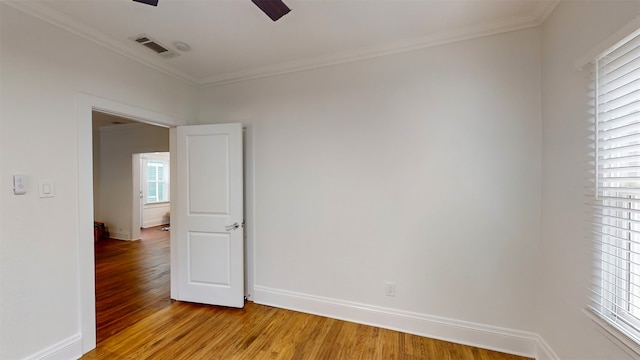 empty room with a wealth of natural light, light hardwood / wood-style floors, and ornamental molding