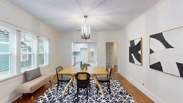 dining space with hardwood / wood-style floors, a notable chandelier, ornamental molding, and a textured ceiling