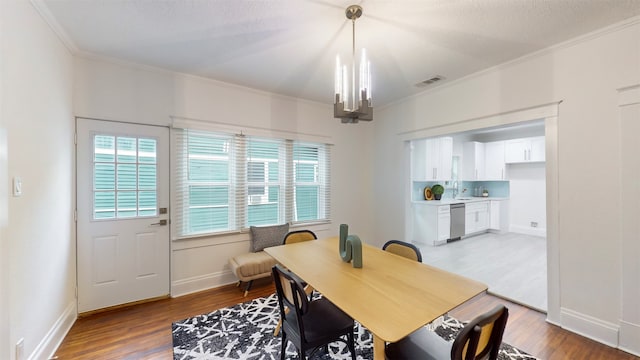 dining room with hardwood / wood-style floors, a chandelier, a textured ceiling, and ornamental molding