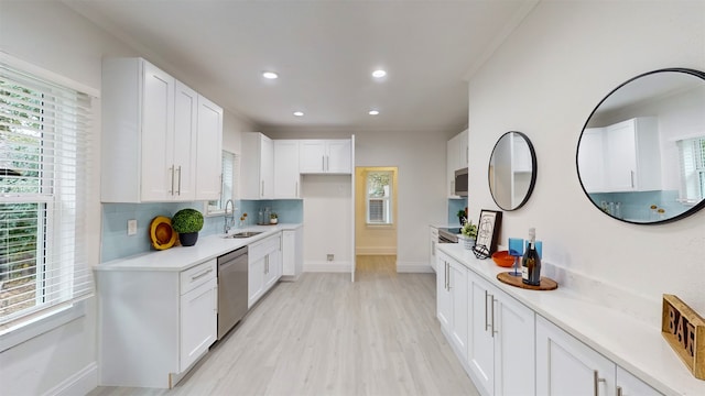 kitchen featuring white cabinetry, decorative backsplash, dishwasher, and light hardwood / wood-style flooring