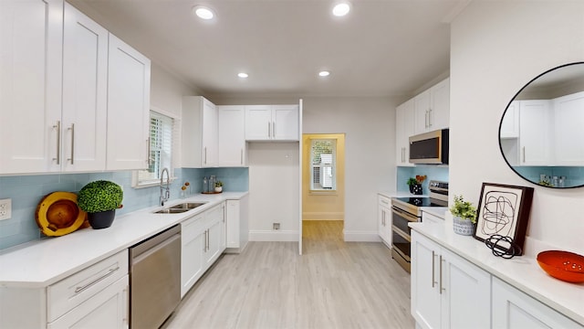 kitchen featuring white cabinetry, sink, appliances with stainless steel finishes, tasteful backsplash, and light hardwood / wood-style flooring