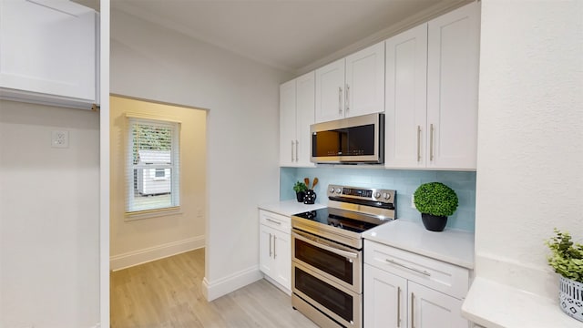 kitchen featuring appliances with stainless steel finishes, decorative backsplash, light hardwood / wood-style floors, and white cabinets