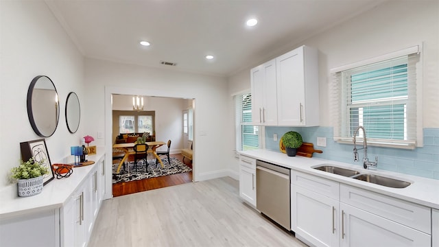 kitchen featuring tasteful backsplash, white cabinetry, light wood-type flooring, sink, and dishwasher