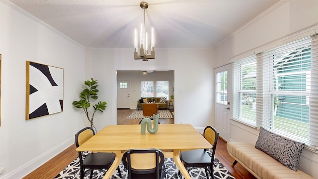 dining space featuring wood-type flooring, an inviting chandelier, and ornamental molding