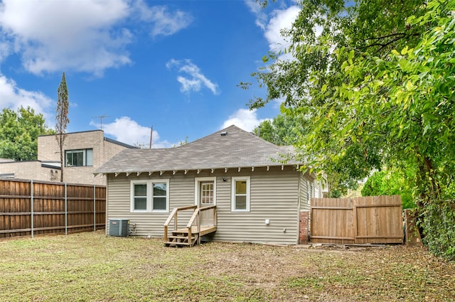 rear view of property featuring central AC unit and a yard