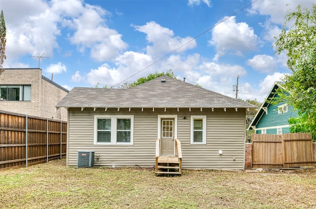 back of house with cooling unit and a lawn