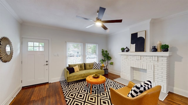 living room featuring ceiling fan, hardwood / wood-style floors, crown molding, and a fireplace