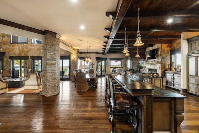 kitchen with ornate columns, pendant lighting, a kitchen bar, a notable chandelier, and dark wood-type flooring