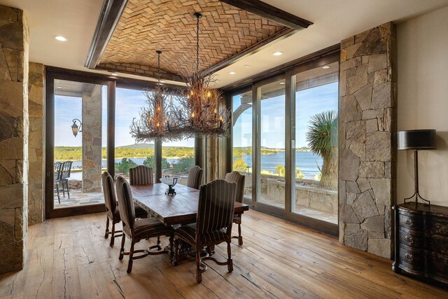 dining area with brick ceiling, a water view, floor to ceiling windows, and light hardwood / wood-style floors