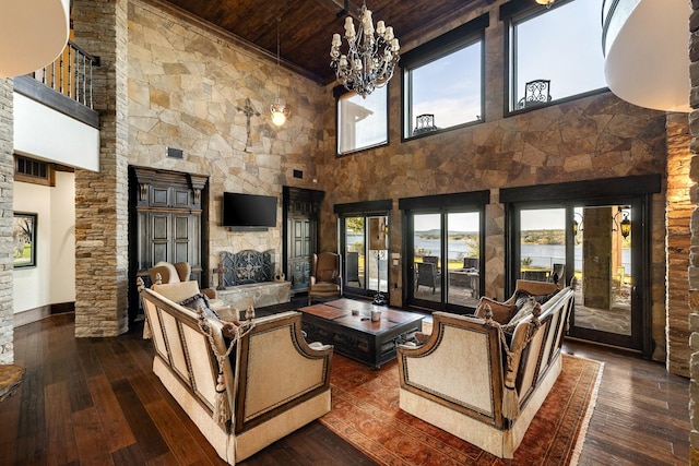 living room featuring a healthy amount of sunlight, a stone fireplace, and dark hardwood / wood-style flooring