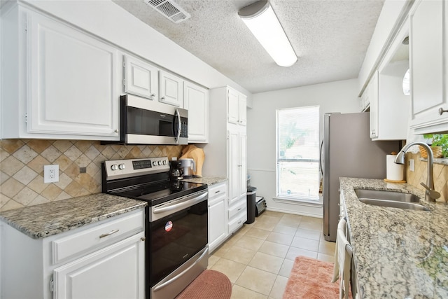 kitchen featuring white cabinets, sink, decorative backsplash, appliances with stainless steel finishes, and light tile patterned flooring