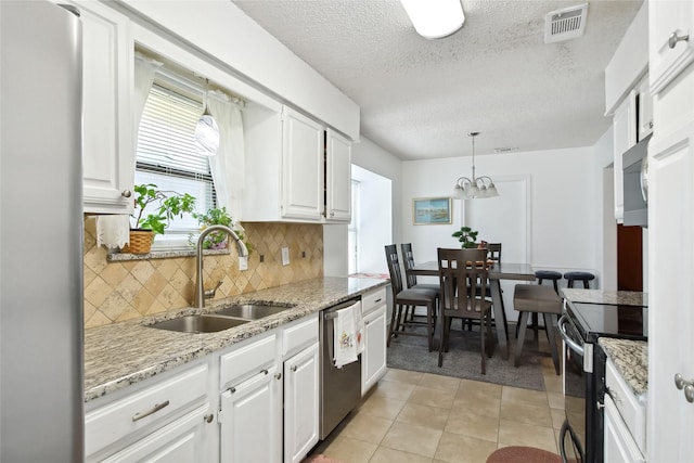 kitchen featuring stainless steel appliances, sink, light tile patterned floors, white cabinetry, and hanging light fixtures