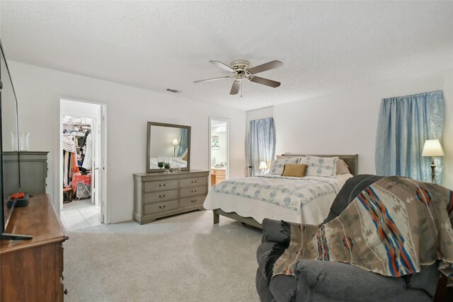 bedroom with a textured ceiling, ceiling fan, and light carpet