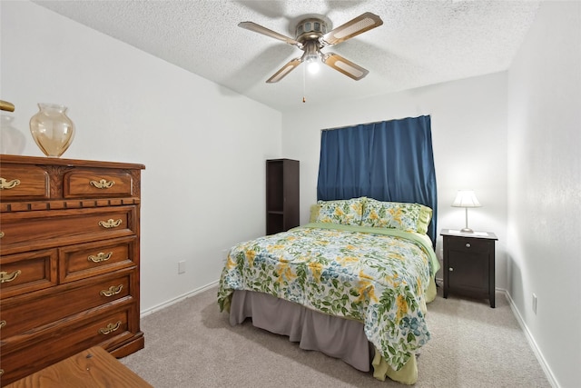 bedroom with ceiling fan, a textured ceiling, and light carpet