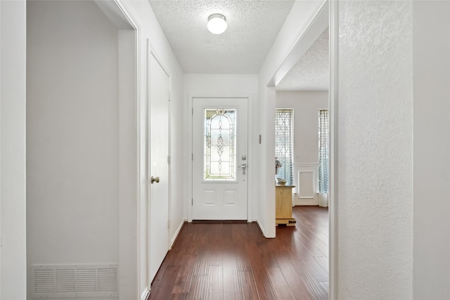 foyer entrance with dark wood-type flooring and a textured ceiling