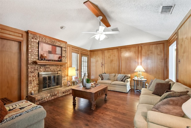 living room featuring a brick fireplace, a textured ceiling, ceiling fan, vaulted ceiling with beams, and dark hardwood / wood-style floors