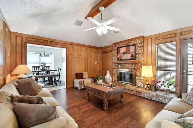 living room featuring a textured ceiling, dark hardwood / wood-style floors, a brick fireplace, and wooden walls