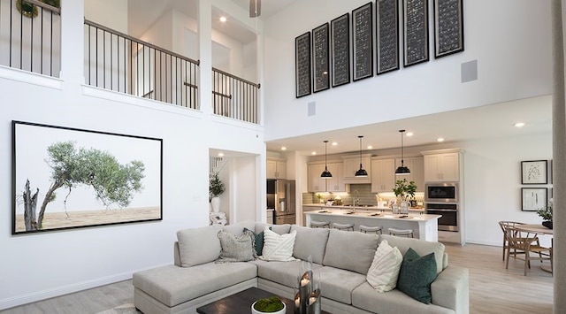 living room with light wood-type flooring and a high ceiling