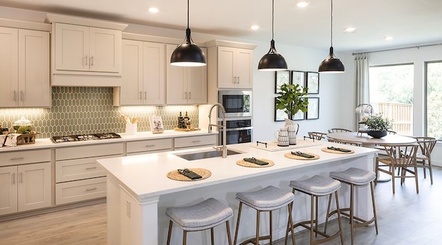 kitchen with a kitchen island with sink, stainless steel appliances, and sink