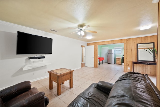 living room featuring ceiling fan, wooden walls, and crown molding