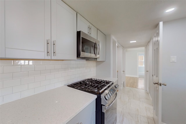 2605 Mark Dr, Mesquite, TX 75150 - kitchen featuring appliances with stainless steel finishes, light stone counters, backsplash, light marble finish flooring, and white cabinetry