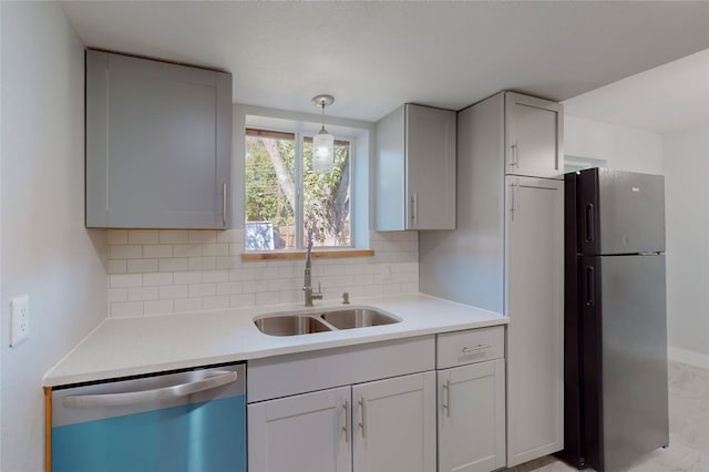 kitchen with decorative backsplash, sink, gray cabinetry, pendant lighting, and appliances with stainless steel finishes